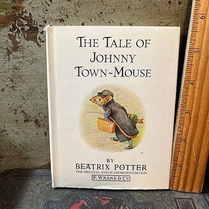 May include: A white book with a black and white illustration of a mouse wearing a hat and carrying a suitcase. The title of the book is "The Tale of Johnny Town-Mouse" by Beatrix Potter. The original and authorized edition by F. Warne & Co.