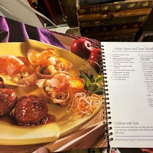 May include: A close-up of a plate of Asian sweet and sour meatballs with a side of noodles. The meatballs are served in wonton cups and are topped with a sweet and sour sauce. The recipe is printed on the page next to the plate.