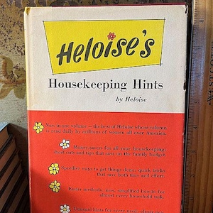 May include: Vintage book titled "Heloise's Housekeeping Hints" with a yellow and red cover. The title is in black script on a yellow rectangle. The book promises money-saving tips and quicker methods for household tasks.
