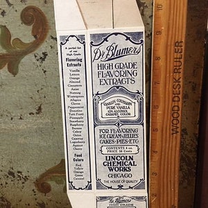 May include: A vintage box of Dr. Blumer's High Grade Flavoring Extracts. The box is white with blue lettering and lists a variety of flavors including vanilla, lemon, orange, almond, cinnamon, anise, nutmeg, wintergreen, allspice, cloves, peppermint, donatino, tutti frutti, pineapple, strawberry, raspberry, banana, celery, onion, caraway, loganberry, apricot, cherry, and food colors. The box also includes instructions for using the extracts to flavor ice cream, jellies, cakes, pies, and other desserts. The box is made by Lincoln Chemical Works in Chicago.