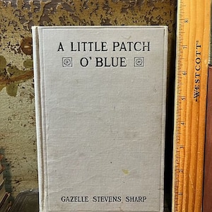 May include: A vintage book titled "A Little Patch O' Blue" by Gazelle Stevens Sharp. The book has a light gray linen cover with a decorative design on the front.