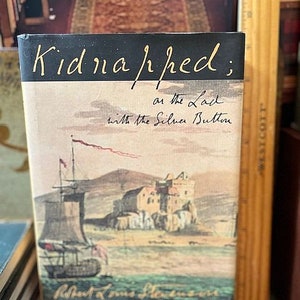 May include: A vintage book cover with the title "Kidnapped; or the Lad with the Silver Button" in black cursive writing. The cover features a watercolor illustration of a ship sailing towards a castle on a rocky shore.