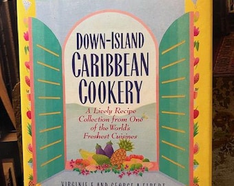 May include: A cookbook titled "Down-Island Caribbean Cookery" with a yellow spine and a colorful cover. The cover features an archway design with turquoise shutters, fruits, and the text "A Lively Recipe Collection from One of the World's Freshest Cuisines."