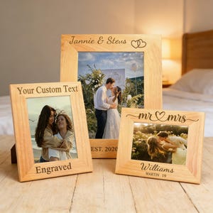 Könnte beinhalten: Drei Holzbilderrahmen mit Fotos von Paaren. Die Rahmen haben eingravierte Texte wie "Jannie & Stevus", "Your Custom Text" und "mr & mrs". Die Rahmen stehen auf einer Holzoberfläche.
