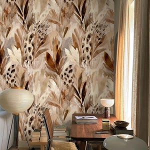 Peut inclure: Une pièce avec un papier peint présentant un motif répétitif de feuilles abstraites dans des tons de marron, beige et crème. Un bureau en bois, une chaise et un lampadaire sont dans la pièce. La pièce a une palette de couleurs neutres.