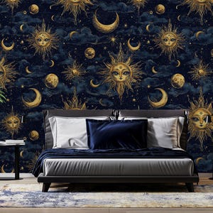 Op de afbeelding: Een donkerblauwe behang met een gouden hemels patroon met zonnen, manen en sterren. Voor de behang staat een bed met een donkerblauwe hoofdeinde en donkerblauwe en witte beddengoed.