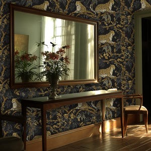 May include: A room decorated with dark wallpaper showcasing a repeating pattern of leopards and foliage in gold and black. A wooden table, chair, and mirror are present, creating a luxurious and exotic atmosphere. The room is lit by natural light.