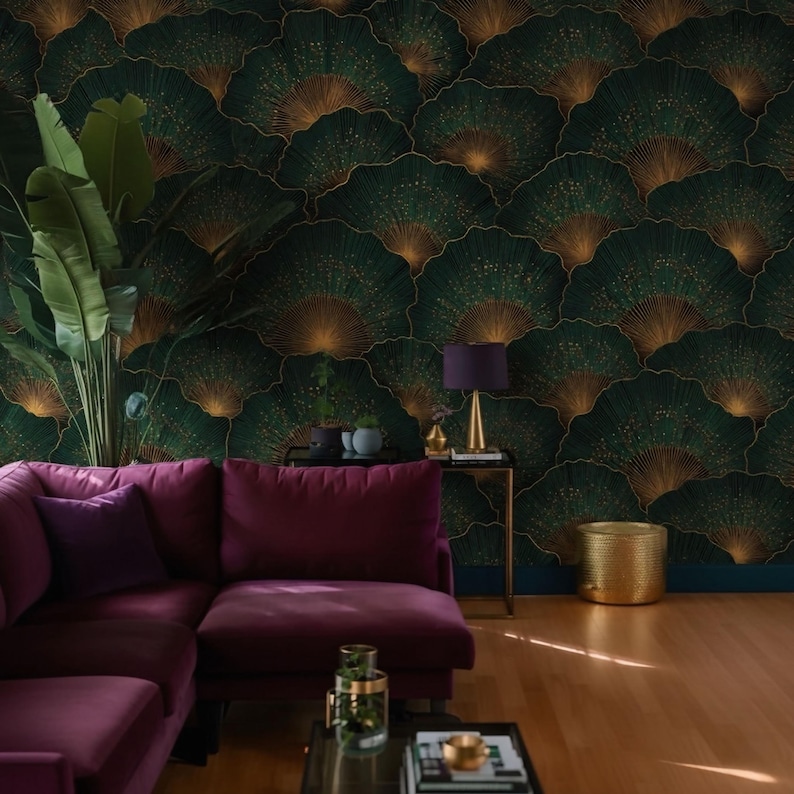 May include: A living room featuring a dark green wallpaper with a fan-like pattern in gold. A plum-colored sectional sofa is in the foreground, with a gold side table and lamp. A gold wastebasket and a large potted plant complete the scene.