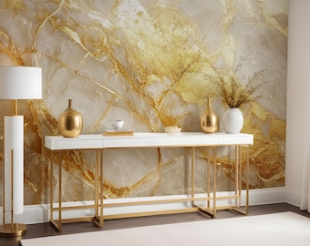 May include: A white console table with gold metal legs and a marble-patterned wallpaper backdrop. The table is decorated with two gold vases, a small white bowl, and a white lamp with a gold base.