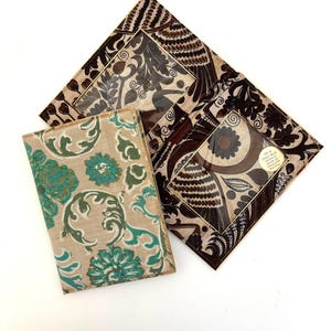May include: Three vintage fabric items with floral and geometric patterns. One is a beige and teal floral design, while the others feature brown and beige patterns. The items are arranged on a white surface.