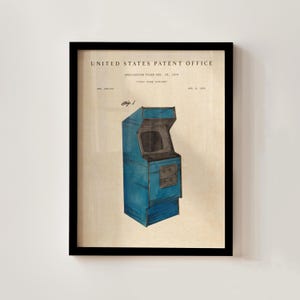 Op de afbeelding: Ingelijste print van een vintage arcade game cabinet patent illustratie. De blauwe kast is afgebeeld met een scherm en bedieningspaneel. De tekst "United States Patent Office" staat bovenaan, met applicatie details.