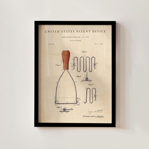 Puede incluir: Impresión enmarcada de una patente de un pasapurés antiguo de la Oficina de Patentes de los Estados Unidos. La impresión presenta dibujos técnicos detallados del pasapurés, con un mango de madera y componentes metálicos. La fecha de solicitud de patente es el 14 de abril de 1930.