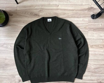 May include: A dark green v-neck sweater with a small green crocodile logo on the left chest.