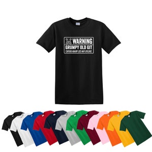 Puede incluir: Una camiseta negra con un gráfico blanco que dice "Warning Grumpy Old Git Contains Memory Loss and Flatulence". El gráfico es una calavera y huesos cruzados. La camiseta está disponible en una variedad de colores.
