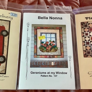 May include: Three quilt pattern covers in plastic sleeves. The first features a red truck with a Christmas tree and the text "Special Delivery". The second cover says "Bella Nonna" and shows a quilt with geraniums. The third cover says "Plaid Patch!" and shows a star quilt.