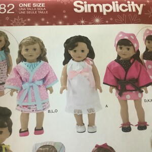 May include: Simplicity sewing pattern featuring doll clothes. The pattern includes various outfits, such as a pink robe with blue trim, a white dress with lace, and a pink polka dot outfit. The pattern is one size.