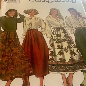 May include: Simplicity sewing pattern featuring four women's skirt and blouse designs. The skirts vary in color and pattern, including floral and solid options. The blouses are white and long-sleeved. The pattern is labeled with the brand name "Simplicity".
