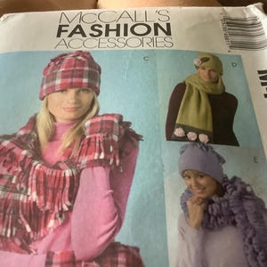May include: McCall's Fashion Accessories pattern featuring hats, scarves, and gloves. The pattern includes a pink and red plaid hat, scarf, and gloves set. Other sets include a green scarf with floral accents and a purple hat and scarf set.