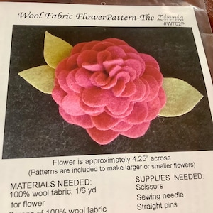 May include: A craft kit for a wool fabric flower pattern, the Zinnia. The flower is approximately 4.25 inches across, with a pink flower and two light green leaves. The kit includes instructions and materials for making the flower.