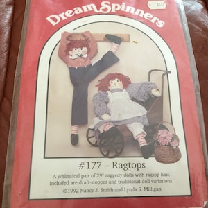 May include: A package for Dream Spinners #177 Ragtops. The package features two rag dolls, one in a wagon and the other posed. The dolls have red hair and are approximately 29 inches tall. The package includes draft-stopper and traditional doll variations.