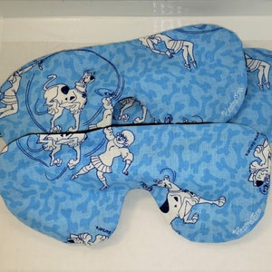 May include: Two blue sleep masks with a white background featuring a cartoon dog and a girl. The masks have black elastic straps.