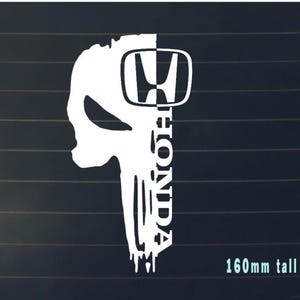 May include: White vinyl decal of a skull with the Honda logo on the right side of the skull. The word "Honda" is written vertically on the right side of the skull. The decal is 160mm tall.