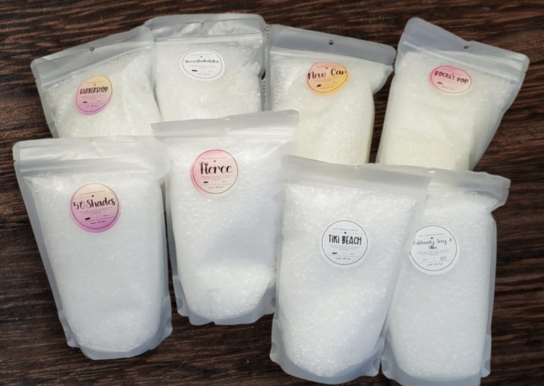 May include: Eight clear plastic bags filled with white bath salts. Each bag has a round label with a different scent name: "Barbershop", "Brown Sugar Vanilla", "New Car", "Rocket Pop", "50 Shades", "Fierce", "Tiki Beach", and "Deliciously Sangria".
