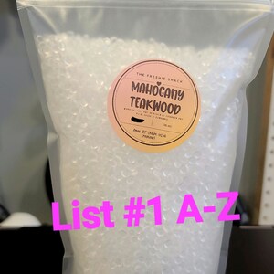 May include: A clear plastic bag filled with small, white, round beads. The bag has a label that says "The Freshie Shack Mahogany Teakwood" with a pink heart. The label also says "16 oz" and "love it? leave us a review!"