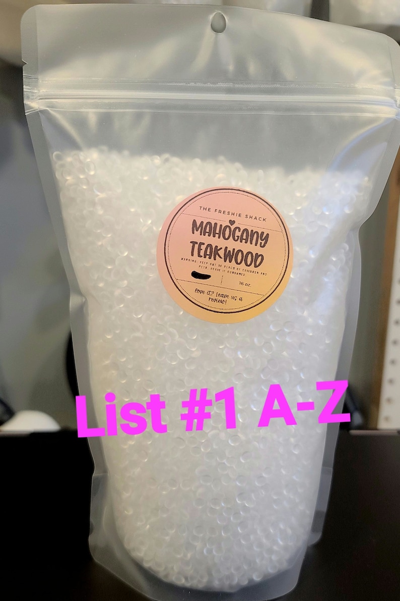 May include: A clear plastic bag filled with small, white, round beads. The bag has a label that says "The Freshie Shack Mahogany Teakwood" with a pink heart. The label also says "16 oz" and "love it? leave us a review!"