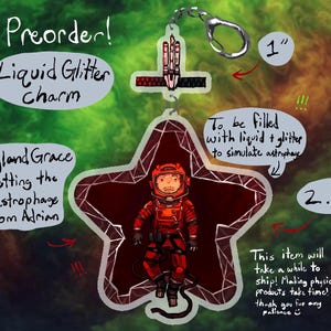 May include: A pre-order liquid glitter charm in the shape of a star, featuring an astronaut in a red spacesuit. The charm is 2.5 inches tall and 1 inch wide, with text that reads "Ryland Grace getting the astrophage from Adrian."
