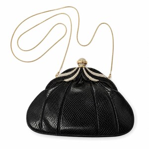 Könnte beinhalten: Eine schwarze Clutch mit texturiertem Schlangenledermuster, ausgestattet mit einem goldfarbenen Metallrahmen und einem langen, dünnen Goldkettengriff. Der Verschluss ist mit klaren Kristallen in Fächerform und einem runden Kristallbesatz verziert.