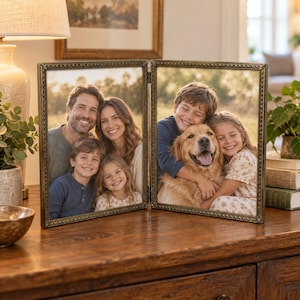 Puede incluir: Un marco de fotos doble de metal con estilo antiguo y un borde texturizado que imita una cuerda. El marco contiene dos fotografías separadas: una muestra a una familia de cuatro personas y la otra a un niño abrazando a un perro golden retriever.