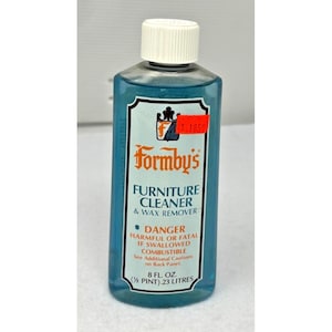 Puede incluir: Una botella de plástico transparente de Formby's Furniture Cleaner & Wax Remover. La botella tiene una tapa blanca y un líquido azul en su interior. La etiqueta incluye el texto "DANGER" y "8 FL. OZ. (½ PINT) .23 LITRES". Una etiqueta de precio roja está adjunta.
