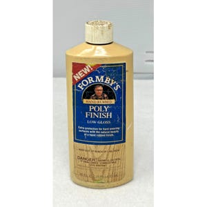 Könnte beinhalten: Eine Flasche Formby's Poly Finish, geringer Glanz, mit beigem Körper und weißem Verschluss. Das blaue Etikett hat weißen und roten Text, einschließlich "NEW!" und "HAND RUBBED". Die Flasche enthält 473 ml.
