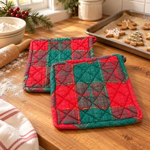 May include: Two square quilted pot holders featuring a red and green plaid pattern with thin gold metallic thread accents. The fabric has a stitched diamond grid texture throughout, providing a soft and functional surface for handling hot kitchen items.
