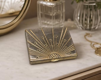 Polvos compactos cuadrados Estée Lauder Vintage Sunburst Celestial en tono dorado y plateado.