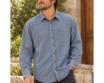 Puede incluir: Una camisa de manga larga en mezclilla azul con un bolsillo en el pecho, cuello clásico y tapeta de botones frontal. La camisa se combina con una gorra de béisbol de dos tonos con visera marrón y corona oscura.