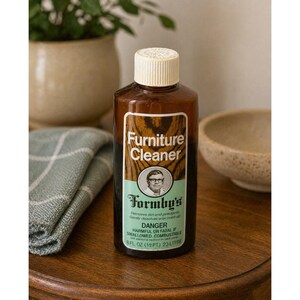 Op de afbeelding: Een bruine plastic fles Formby's Furniture Cleaner met een wit etiket en dop. Het etiket bevat de tekst "Furniture Cleaner" en een portret. De fles bevat 23 liter.