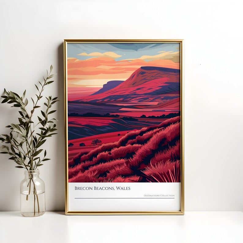 May include: A framed illustration of a mountain range with a sunset sky. The mountains are a deep red and purple color, and the sky is a mix of orange, yellow, and pink. The text "Brecon Beacons, Wales" is at the bottom of the image.