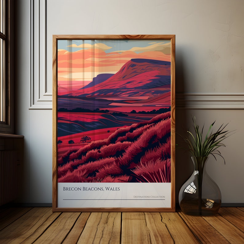 May include: A framed illustration of a mountain range with a sunset sky. The mountains are a deep red color, and the sky is a mix of orange, pink, and purple. The text "Brecon Beacons, Wales" is at the bottom of the image.