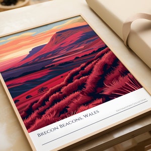 May include: A framed illustration of a mountain range with a red, pink, and purple color scheme. The text "BRECON BEACONS, WALES" is at the bottom of the image. The text "DESTINATIONS COLLECTION" is in the bottom right corner.