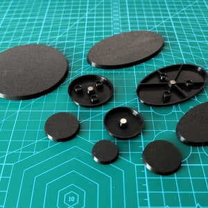 Può includere: Un set di nove basi rotonde e ovali nere per miniature. Le basi sono in plastica e hanno una finitura liscia e opaca. Alcune delle basi hanno un piccolo magnete incorporato al centro.