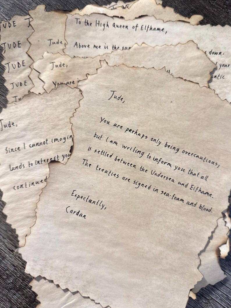 May include: A collection of aged paper notes with handwritten text. The edges of the paper are singed, giving them a vintage appearance. The text includes phrases like "To the High Queen of Elfhame" and "The treaties are signed in sea-foam and blood."