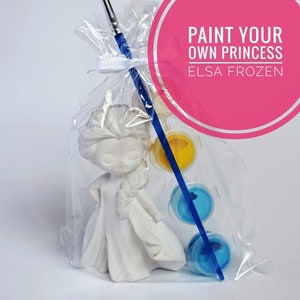 May include: A white paint-your-own Elsa figurine from Frozen, with blue and yellow paint pots and a paintbrush, all packaged in a clear plastic bag. The bag has a pink circle label that says "Paint Your Own Princess Elsa Frozen".