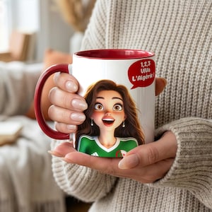 Peut inclure: Mug en céramique blanche avec intérieur et anse rouges. La tasse présente une illustration de dessin animé d'une femme portant un maillot vert et blanc. Une bulle rouge affiche le texte "1,2,3 Viva L'Algérie!"
