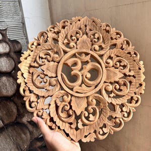 精巧に手彫りされた Om Kara 壁掛け – 精神的な調和をもたらす花のモチーフをあしらった円形の木製アート