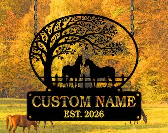 Può includere: Cartello in metallo nero con un albero e due cavalli all'interno di una cornice ovale, sospeso da catene. Il cartello include il testo "CUSTOM NAME" e "EST. 2026" su una placca rettangolare. Lo sfondo mostra un campo e alberi autunnali.