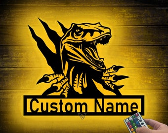 May include: Black and yellow dinosaur-themed wall art with the text "Custom Name". The artwork features a detailed illustration of a dinosaur with its mouth open and claws extended. A remote control is visible in the bottom right corner.