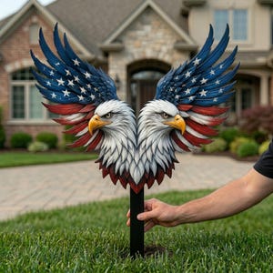 Puede incluir: Una estaca de jardín patriótica con dos águilas calvas con las alas extendidas. Las alas están pintadas con el diseño de la bandera estadounidense, con azul, estrellas blancas y rayas rojas. Las águilas tienen plumas blancas, picos amarillos y están montadas en un poste negro.