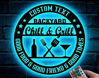 Könnte beinhalten: Ein rundes, schwarzes Metallschild mit blauem Leuchten. Das Schild zeigt "CUSTOM TEXT BACKYARD Chill & Grill GOOD FOOD & GOOD FRIEND & GOOD TIMES". Auf dem Schild sind Sterne, eine Flasche, eine Gabel, ein Spatel und ein Martini-Glas zu sehen.